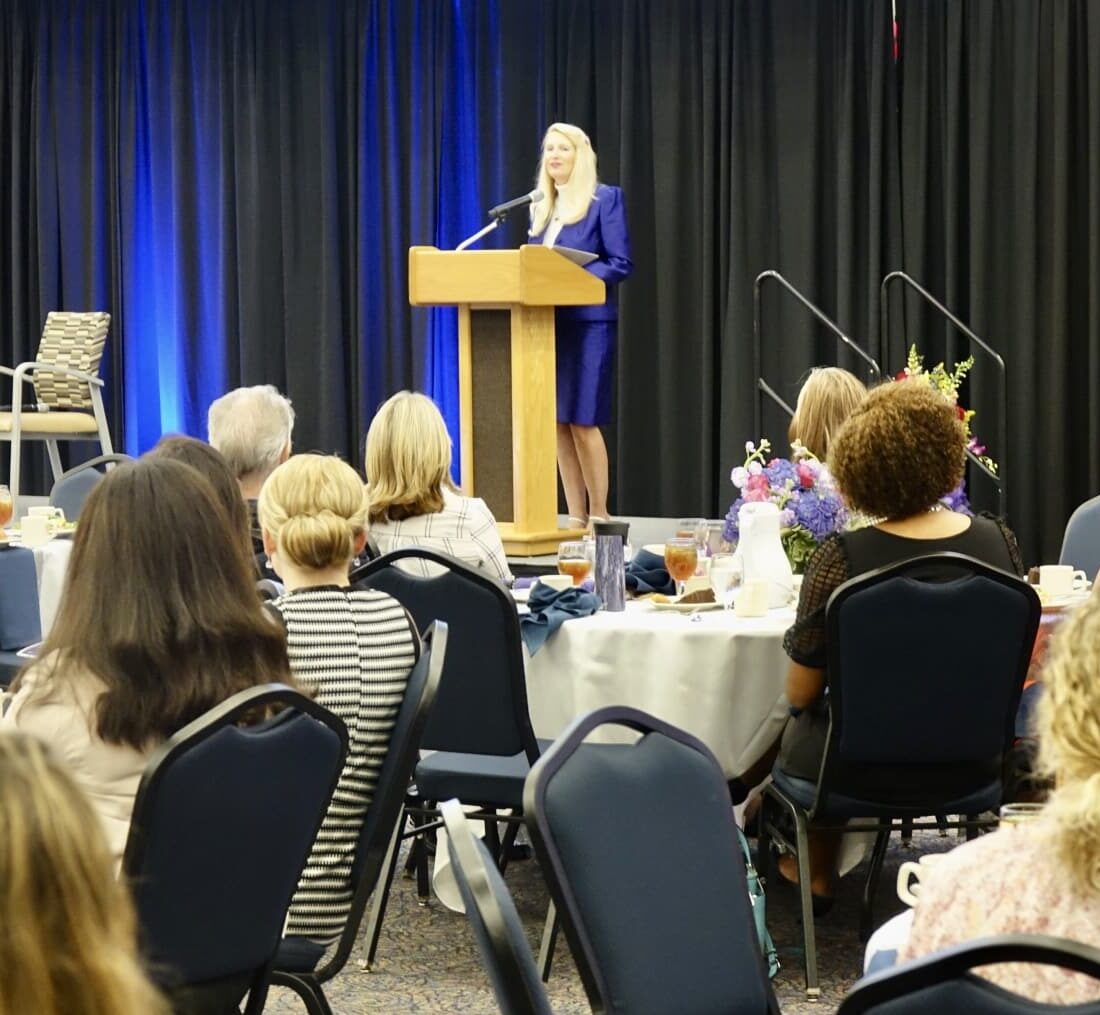 Snowden McFall delivering a leadership and resilience keynote on stage to a full professional audience at a corporate luncheon event.